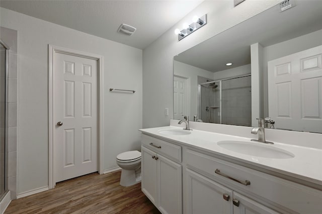 bathroom featuring vanity, a shower with shower door, hardwood / wood-style floors, and toilet