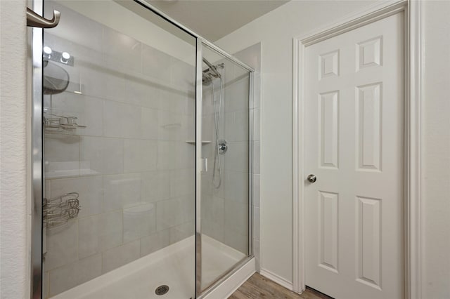 bathroom with hardwood / wood-style flooring and a shower with shower door