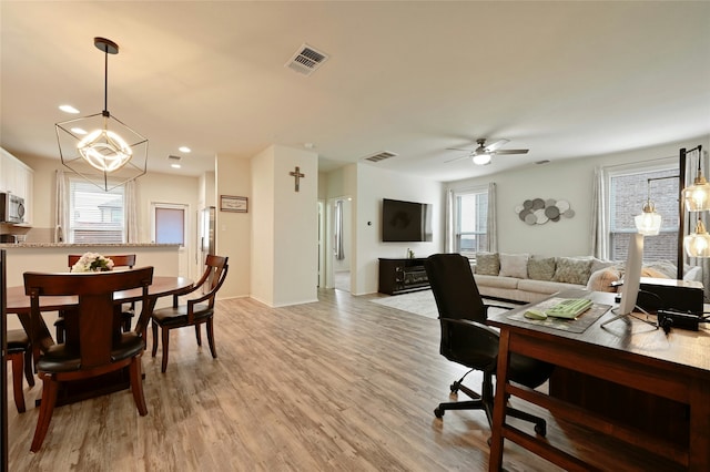 dining space with light hardwood / wood-style floors and ceiling fan with notable chandelier