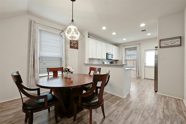 dining room with sink, light wood-type flooring, and lofted ceiling