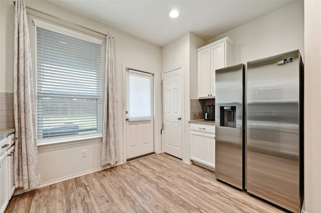 kitchen featuring light stone countertops, white cabinets, decorative backsplash, light hardwood / wood-style floors, and stainless steel fridge with ice dispenser