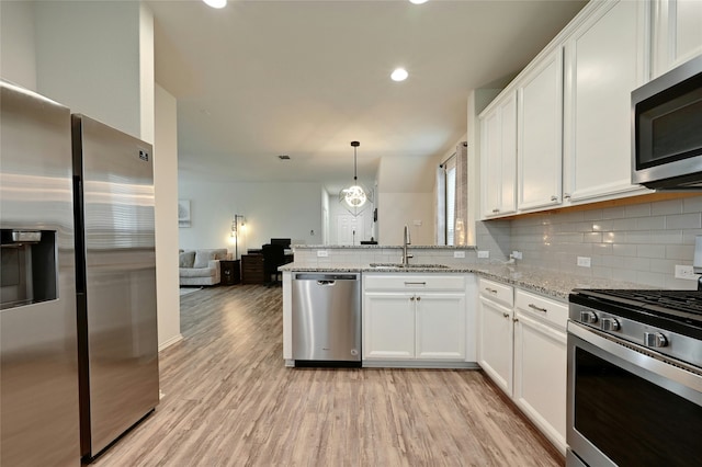 kitchen with light stone countertops, white cabinetry, appliances with stainless steel finishes, and sink