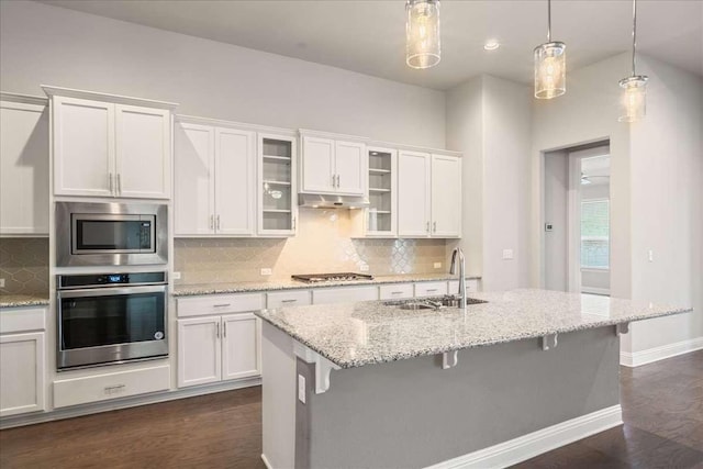 kitchen with a kitchen bar, white cabinetry, hanging light fixtures, sink, and stainless steel appliances