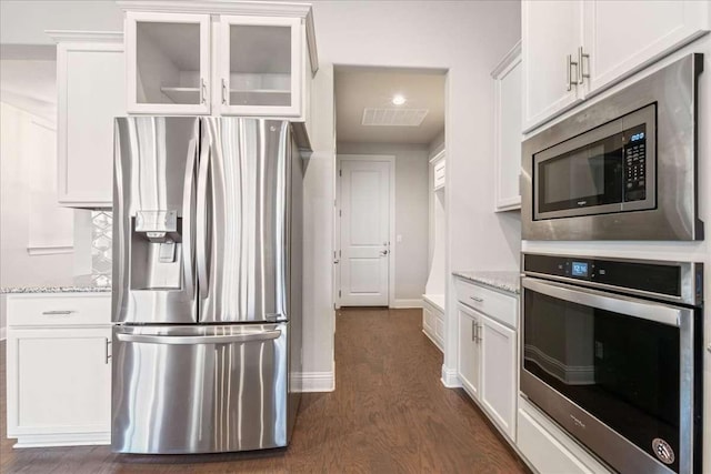 kitchen with white cabinets, dark hardwood / wood-style floors, light stone counters, and appliances with stainless steel finishes