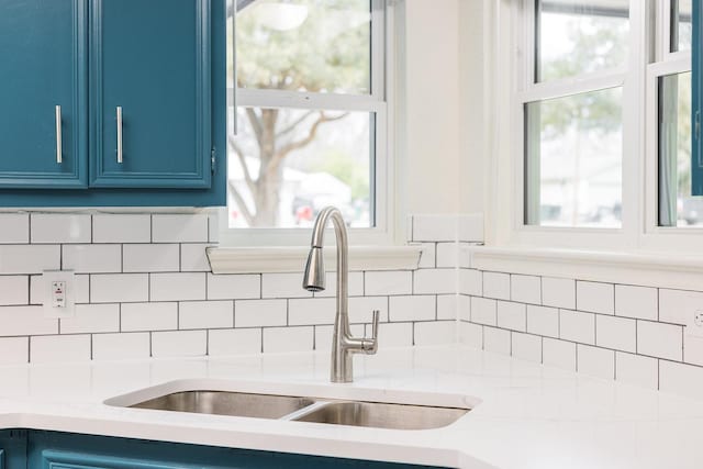 interior details with blue cabinetry, sink, and tasteful backsplash