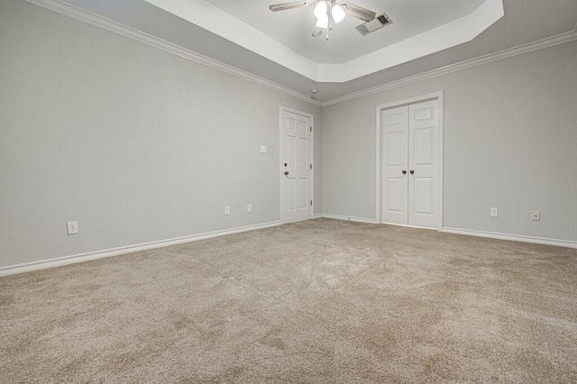 empty room featuring ceiling fan, carpet, crown molding, and a raised ceiling