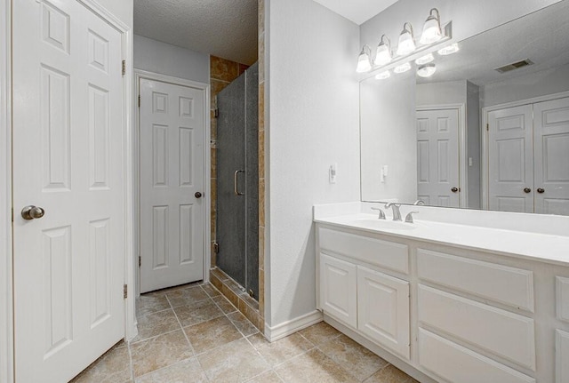 bathroom featuring a textured ceiling, a shower with shower door, and vanity