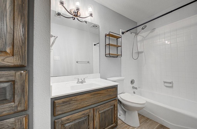 full bathroom with toilet, a textured ceiling, hardwood / wood-style flooring, vanity, and tiled shower / bath