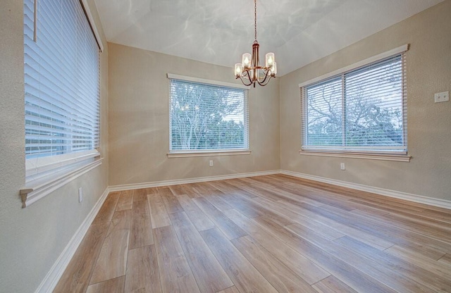 unfurnished room featuring light hardwood / wood-style flooring and an inviting chandelier