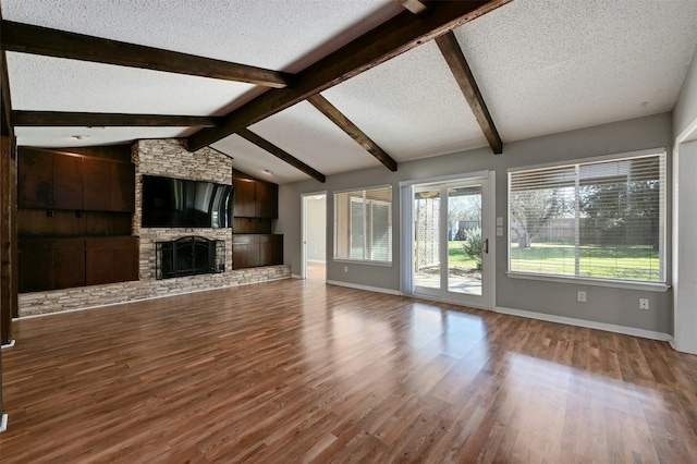 unfurnished living room with a textured ceiling, lofted ceiling with beams, hardwood / wood-style floors, and a fireplace