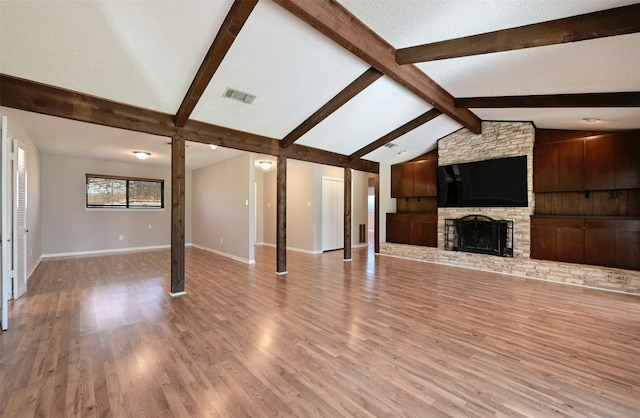 unfurnished living room with light hardwood / wood-style floors, vaulted ceiling with beams, a textured ceiling, and a fireplace