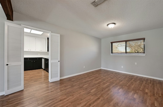 empty room featuring a textured ceiling and dark hardwood / wood-style flooring