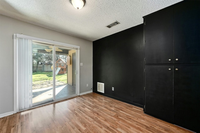 empty room with a textured ceiling and light wood-type flooring