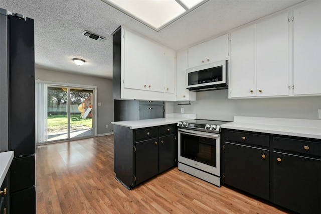 kitchen featuring black fridge, white cabinetry, light hardwood / wood-style flooring, and stainless steel range with electric cooktop