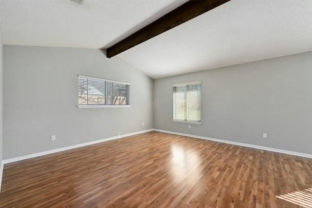 empty room featuring wood-type flooring, a textured ceiling, vaulted ceiling with beams, and a wealth of natural light