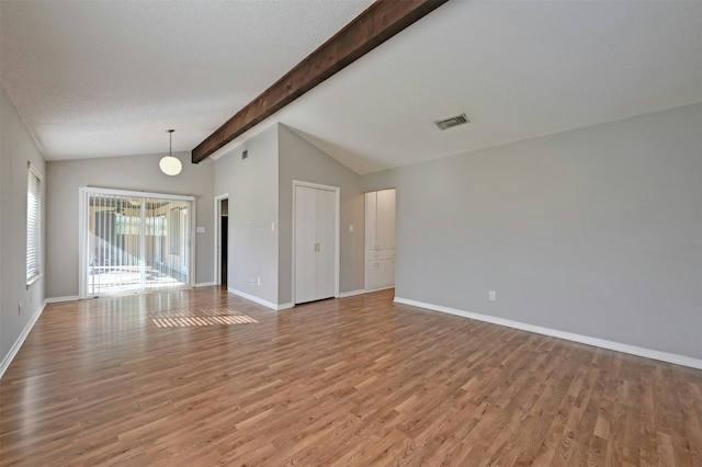 unfurnished room with light hardwood / wood-style floors, a textured ceiling, and lofted ceiling with beams