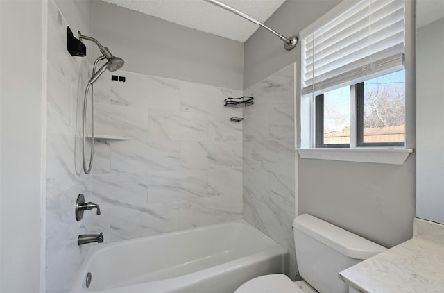 full bathroom featuring a textured ceiling, toilet, tiled shower / bath, and vanity