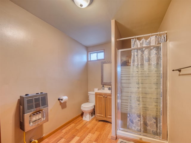 bathroom featuring heating unit, vanity, wood-type flooring, and toilet