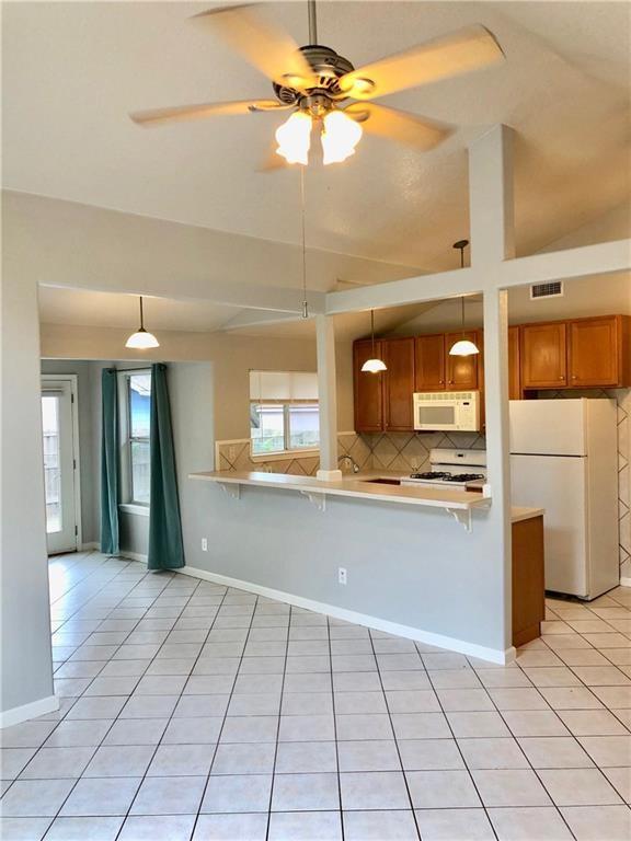 kitchen with pendant lighting, white appliances, light tile patterned floors, and kitchen peninsula