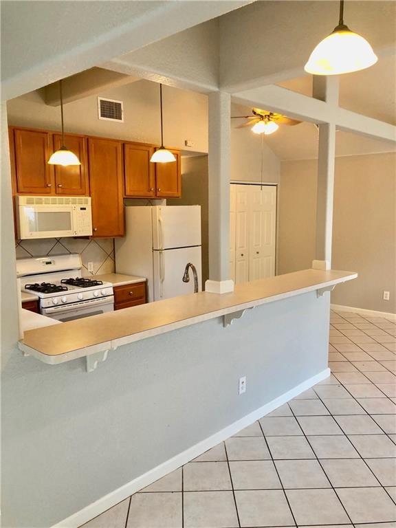 kitchen with white appliances, pendant lighting, and tasteful backsplash