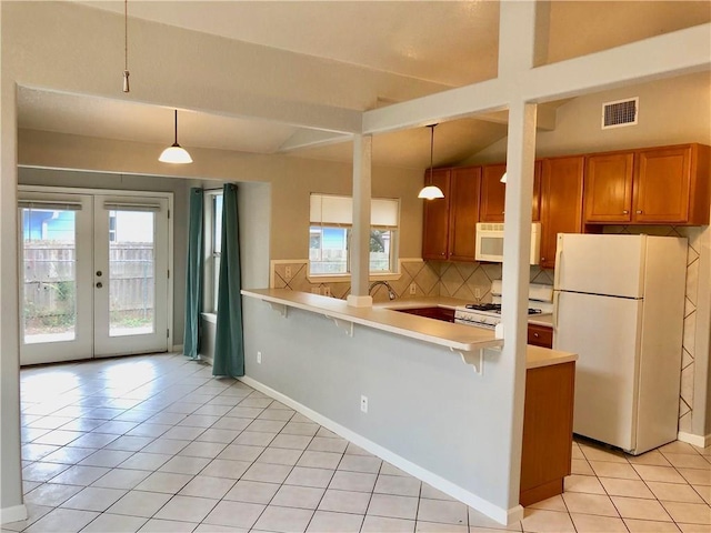 kitchen featuring pendant lighting, white appliances, a kitchen bar, backsplash, and kitchen peninsula