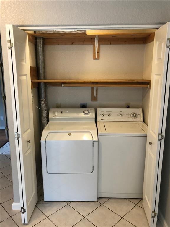 laundry area featuring washer and clothes dryer and light tile patterned floors