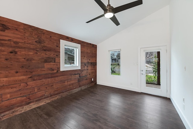 spare room featuring dark wood-type flooring, wooden walls, high vaulted ceiling, and ceiling fan