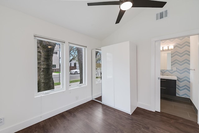 unfurnished bedroom with lofted ceiling, dark hardwood / wood-style floors, ceiling fan, and connected bathroom