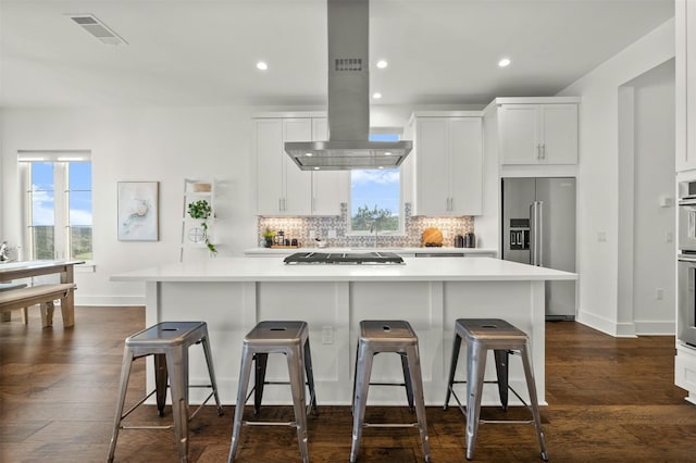 kitchen with a kitchen bar, white cabinetry, appliances with stainless steel finishes, and island range hood