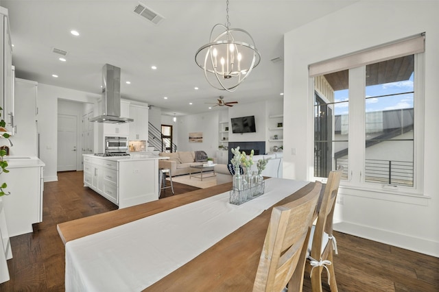 dining room with dark wood-type flooring, plenty of natural light, and ceiling fan with notable chandelier