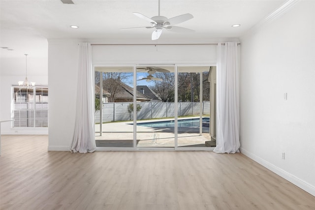 spare room featuring crown molding, ceiling fan with notable chandelier, and light hardwood / wood-style flooring