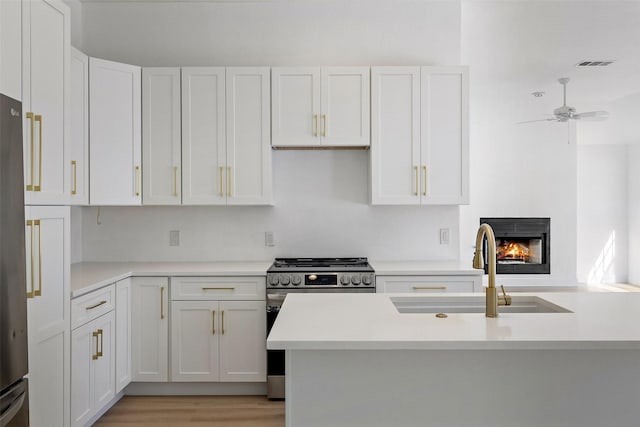 kitchen featuring sink, stainless steel appliances, white cabinetry, and ceiling fan