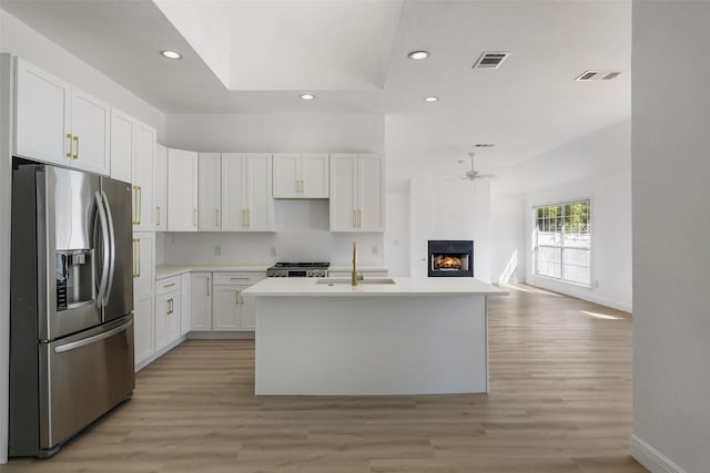 kitchen featuring stainless steel refrigerator with ice dispenser, sink, white cabinetry, and a kitchen island with sink