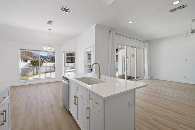 kitchen with dishwasher, sink, decorative light fixtures, light wood-type flooring, and a center island with sink