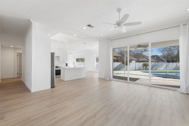 unfurnished living room featuring ceiling fan, sink, and light wood-type flooring