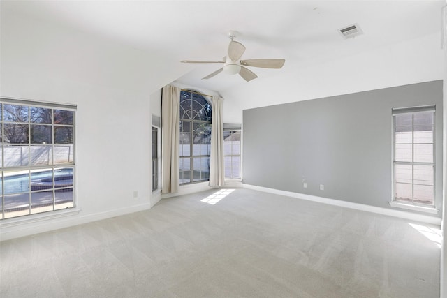 unfurnished room featuring vaulted ceiling, a wealth of natural light, ceiling fan, and light carpet