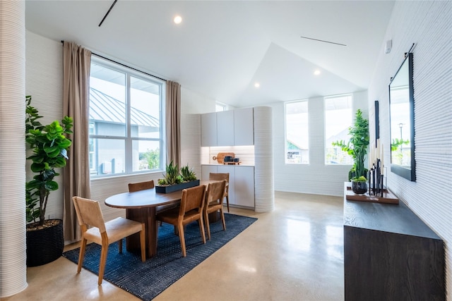 dining space featuring brick wall and vaulted ceiling