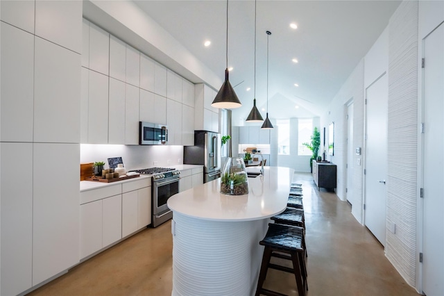 kitchen with hanging light fixtures, appliances with stainless steel finishes, white cabinetry, a kitchen island, and a breakfast bar area