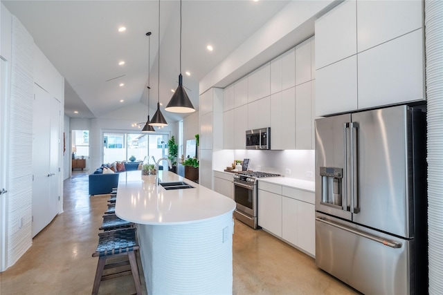 kitchen featuring premium appliances, pendant lighting, sink, white cabinetry, and a kitchen island with sink