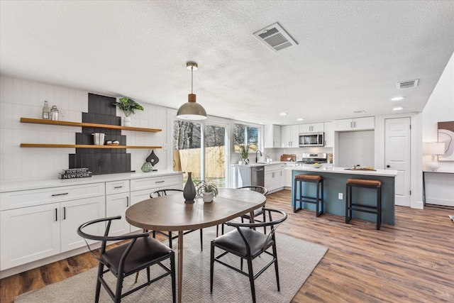 dining area with sink, hardwood / wood-style floors, and a textured ceiling