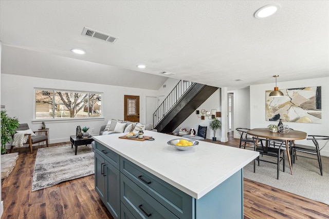 kitchen featuring pendant lighting, blue cabinetry, a center island, dark hardwood / wood-style floors, and lofted ceiling