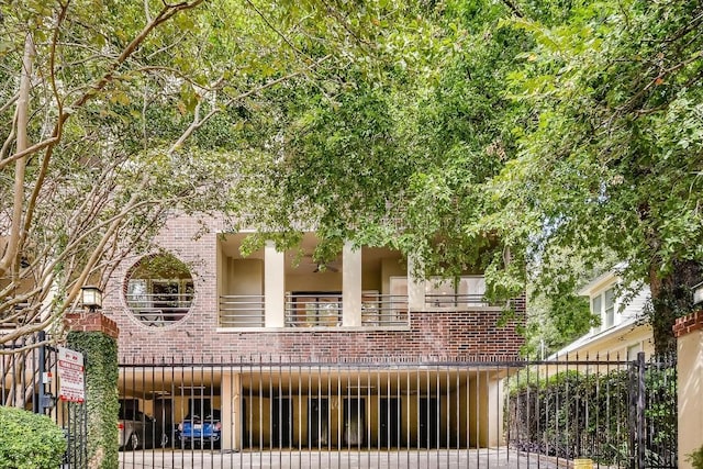 view of front of home featuring brick siding, fence, and a balcony