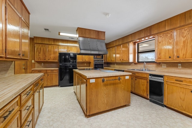 kitchen with exhaust hood, black appliances, a center island, and sink