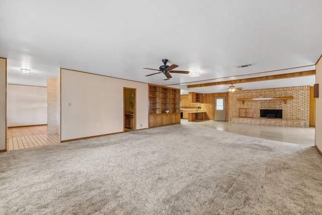 unfurnished living room with a brick fireplace, carpet floors, built in features, and ceiling fan