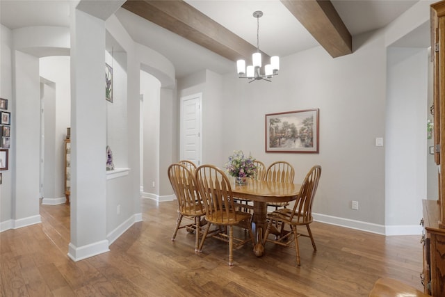 dining space featuring an inviting chandelier, beam ceiling, and hardwood / wood-style floors