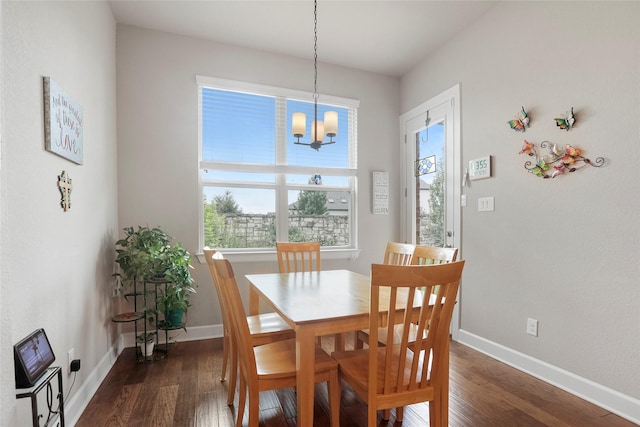 dining space with dark wood-type flooring, a notable chandelier, and a wealth of natural light