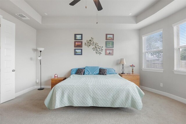 bedroom featuring light colored carpet, ceiling fan, and a raised ceiling