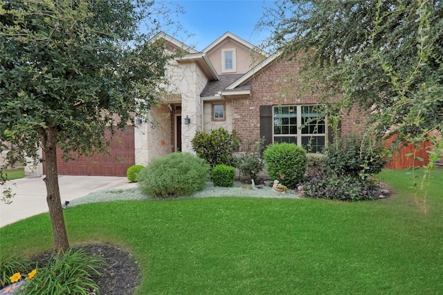 view of front of house with a shingled roof, concrete driveway, a front yard, stone siding, and an attached garage