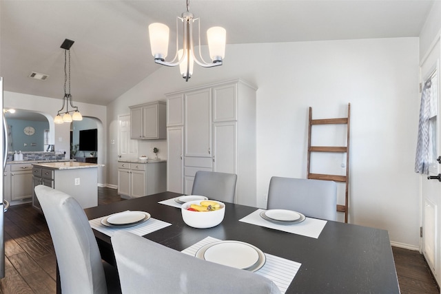 dining space with an inviting chandelier, lofted ceiling, and dark hardwood / wood-style flooring