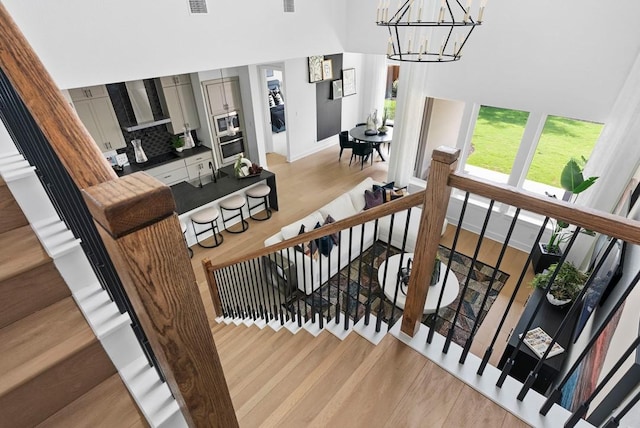 stairway with wood-type flooring and a chandelier